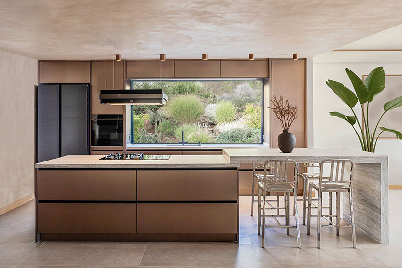 a long kitchen island functions as both preparation and dining space, while the large window frames the garden