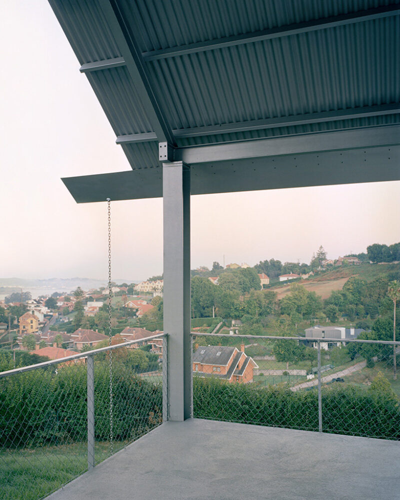 a covered corner terrace frames views over gijón’s suburban terrain