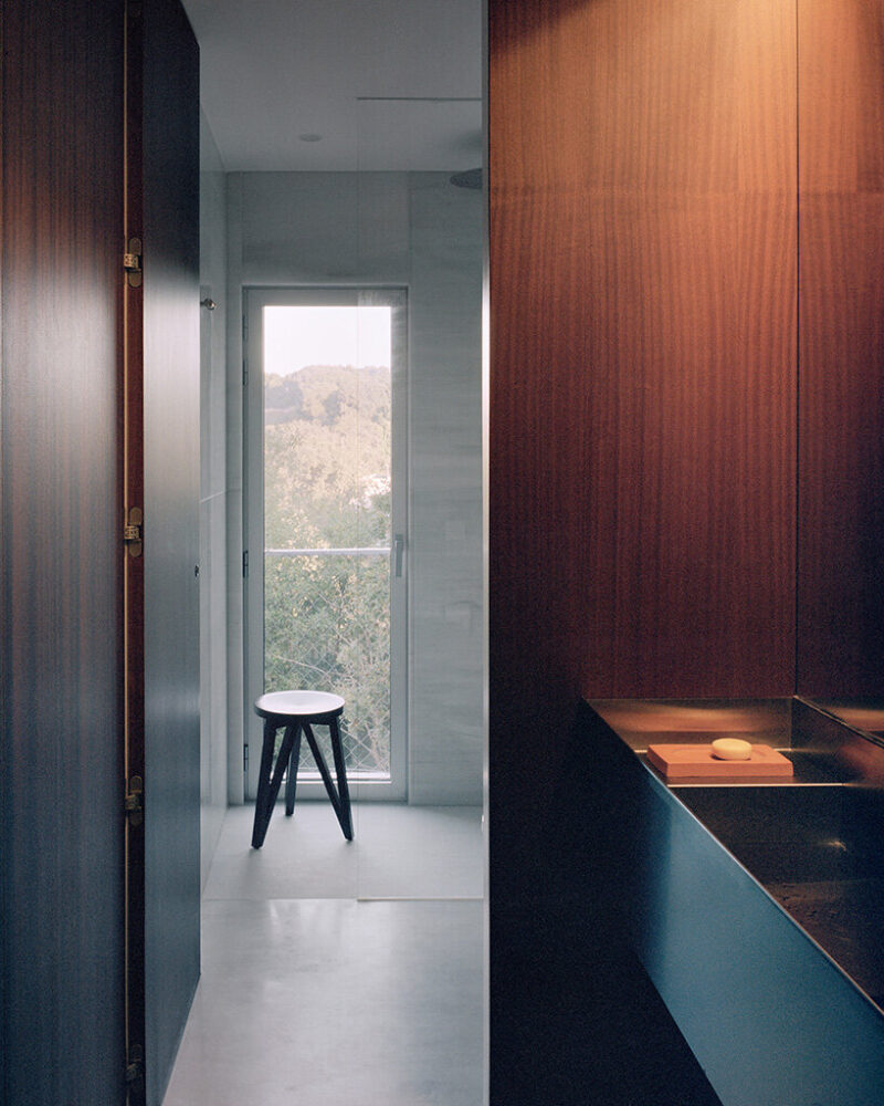 the bathroom frames views of the surrounding greenery through a full-height window