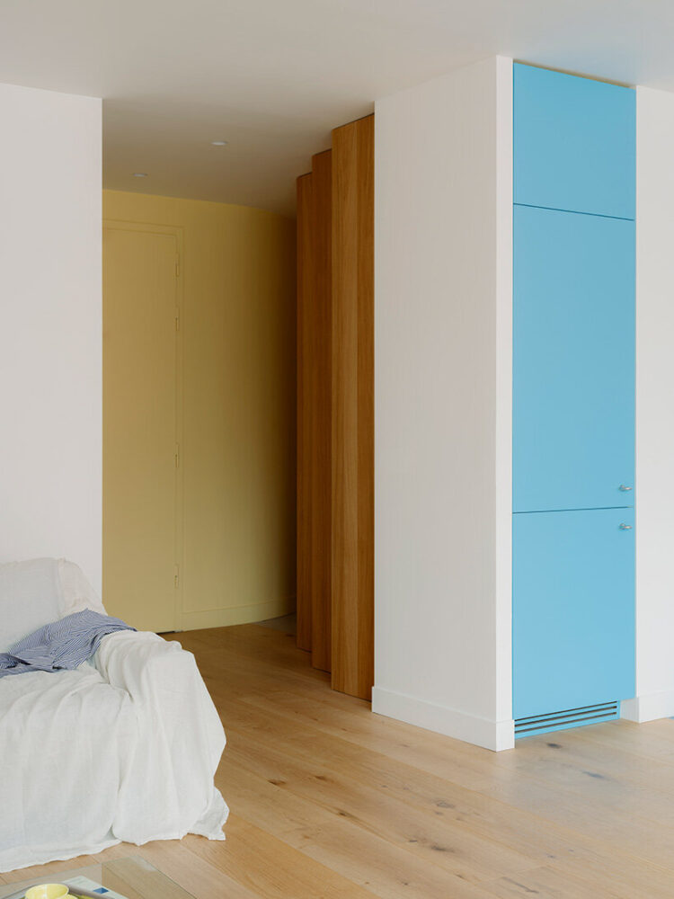 wooden partitions and pastel cabinetry mark the transition between living areas and private spaces