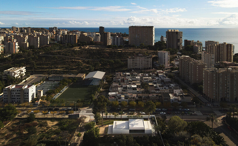 the house sits low within its urban context