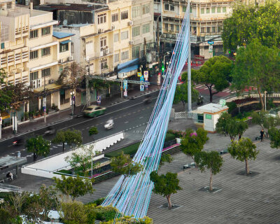 recyclable fabric ribbons weave between bangkok’s streetlights into colorful urban canopy