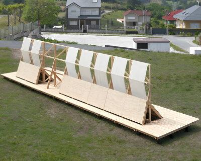 diagonal timber wall installation becomes furniture, shelter, and landscape frame in spain