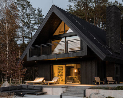 dark timber A&A house reinterprets traditional barn form within polish pine forest