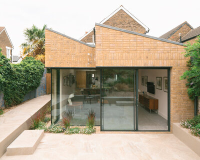 sawtooth roof and textured brick facade reimagine victorian home in the uk