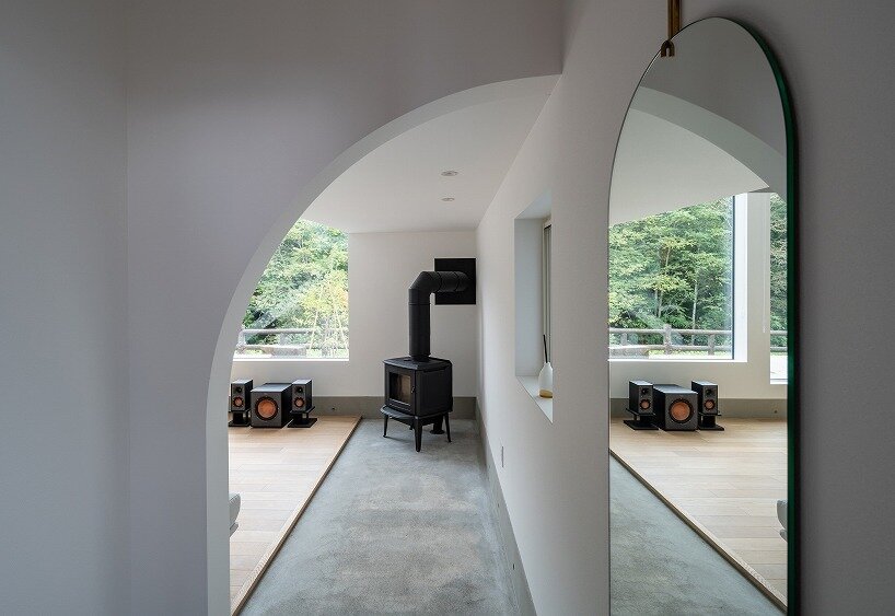 an arched opening frames the wood stove and the forest, creating a calm transition between spaces