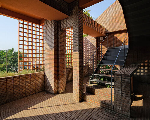 local stone, brick and terracotta screens layer across three-story gathering space in indonesia