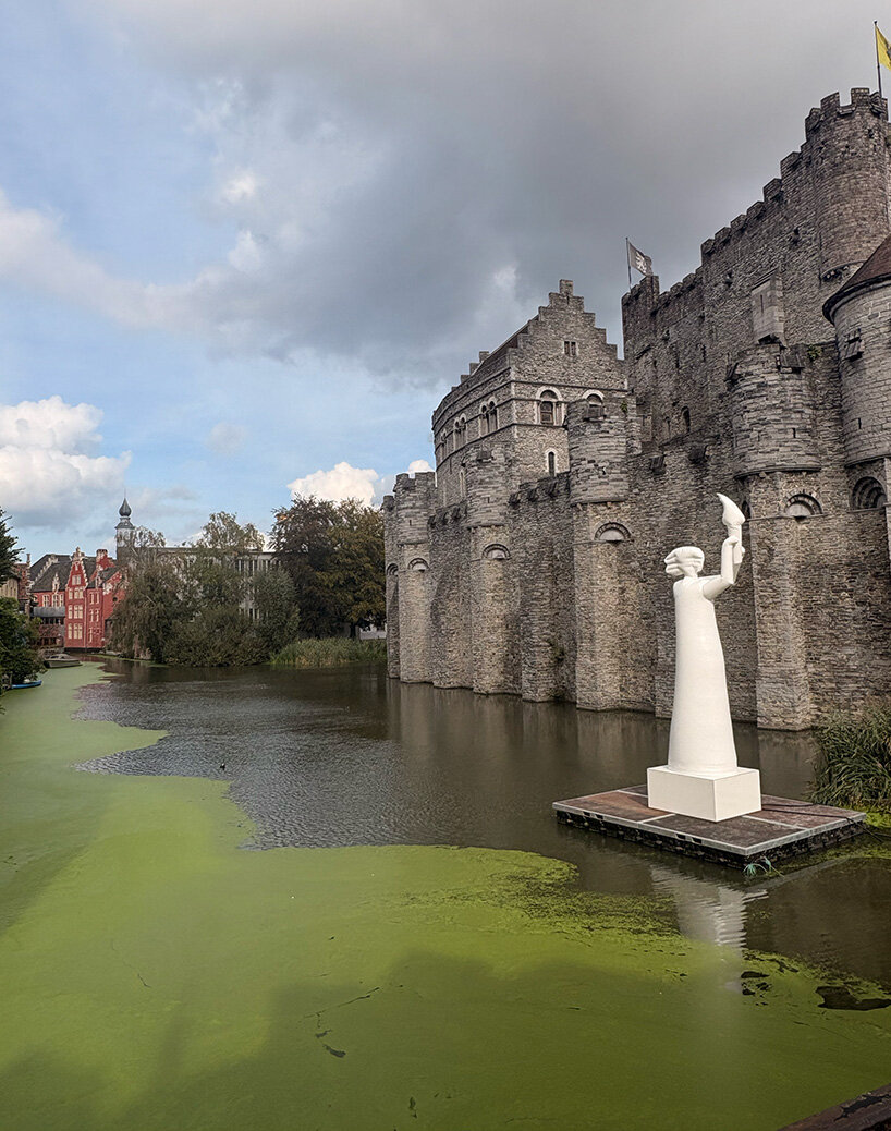     the sculpture sits on a floating platform surrounded by the castle’s medieval architecture