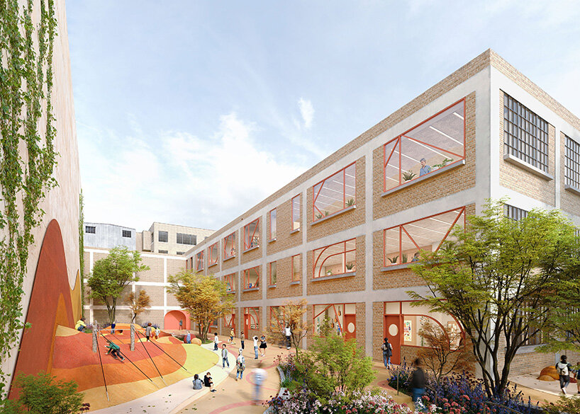  Students play in a landscaped school courtyard with trees, planting beds, colorful geometric structures, and large industrial-style windows